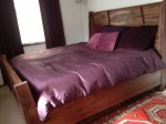 wooden bed with duvet and throw pillows